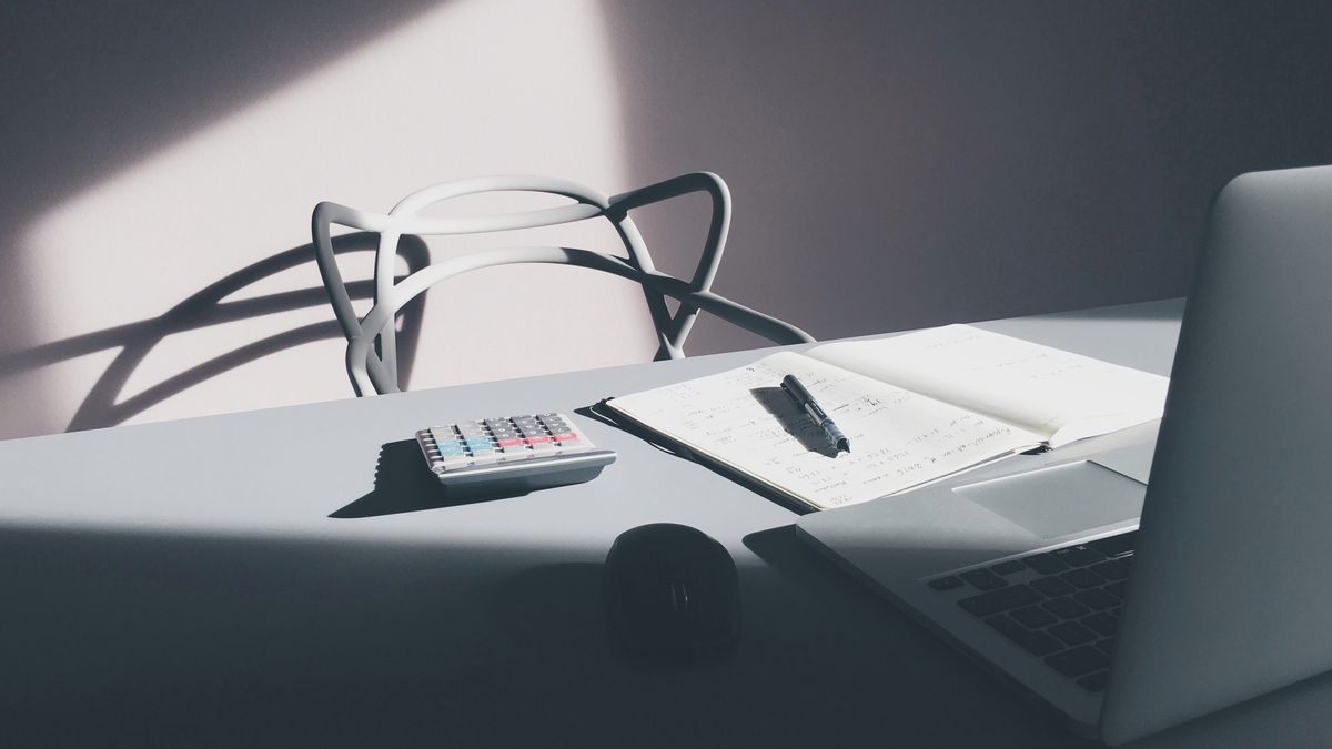 Bureau avec ordinateur portable, calculatrice et carnet de notes